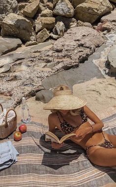 a woman sitting on the beach reading a book