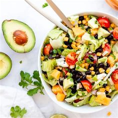 a white bowl filled with salad next to an avocado