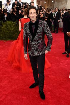 a man in a tuxedo standing on a red carpet