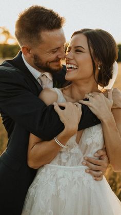 a bride and groom embracing each other in a field