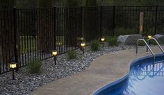 an empty swimming pool with some lights on the side and rocks in the water next to it