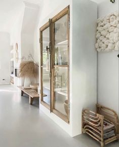 a room with white walls and wooden furniture on the floor next to a large mirror