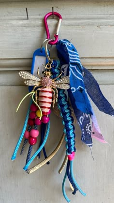 a keychain hanging from the side of a door decorated with beads and ribbons