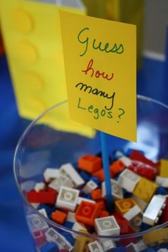 a glass bowl filled with legos and a sign that says guess how many legs?