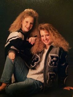 two young women sitting next to each other on the floor with their arms around one another