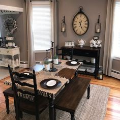 the dining room table is set with place settings for four people and has a clock on the wall