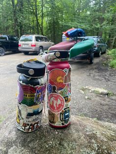 two colorful cans sitting on top of a rock