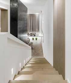 a long hallway with white walls and wooden steps leading up to a living room on the other side