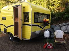 a yellow trailer parked next to a pile of rocks and flowers on the side of it