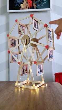 a ferris wheel made out of wood with pictures on the front and sides, sitting on top of a wooden table