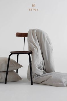 a chair with a blanket over it sitting next to pillows