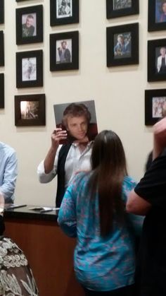 people standing in front of a counter with pictures on the wall behind them and one person taking a photo