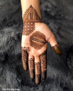 a hand with henna tattoos on it and an intricate design in the middle of its palm