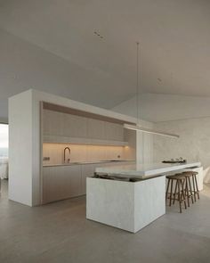 an open kitchen and living room area in a modern house with white walls, flooring and countertops