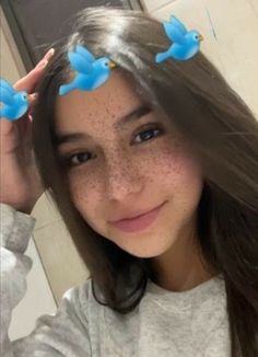 a girl with freckles on her head and two blue birds in the hair