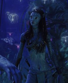 a woman with blue skin and white makeup standing in front of an alien like creature