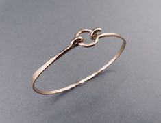 This is a wonderful bangle for layering or to wear alone.  Slightly edgy but with a minimalist feel, the 12 gauge 14kt gold filled wire forms the sturdy base of the bracelet but isn't too bulky.   It's hammered asymmetrically so that it's thicker around the base and sides and narrows at the top of the wrist where it latches onto a small gold ring for a low profile and lots of style.   Easy on-off, and polished to a high shine.   Select YOUR ACTUAL WRIST CIRCUMFERENCE in the dropdown menu and I'll add a bit to fit your wrist size.  If you have any questions about sizing, just convo me. Allow 10 days for fabrication. Note:   Sizes are listed in 1/2 inch ranges.  Bracelet will fit the smaller measurement loosely and the larger measurement snugly but comfortably.  Due to the extremely high pri Metalsmith Jewelry, Metalsmithing Jewelry, Jewelry Minimalist, 12 Gauge, Bracelet Boho, Minimalist Bracelet, Gold Bangle, Gold Price, Hand Forged