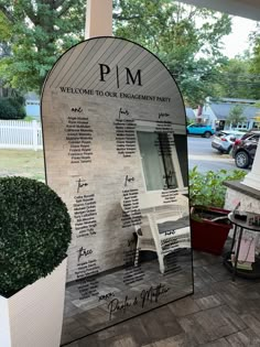 a large mirror sitting on the side of a building next to a potted plant