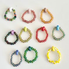 nine bracelets with different colored beads are arranged on a white surface and one is in the middle