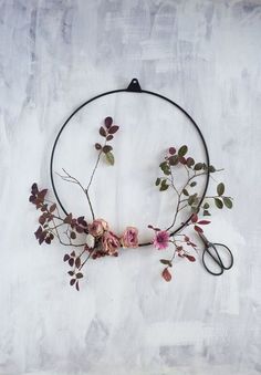 a circular piece of art with flowers and scissors on the side, hanging on a wall