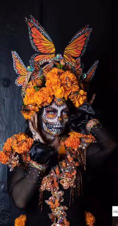 a woman with orange flowers and butterflies on her face is wearing a costume that has been made to look like a butterfly