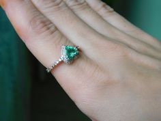 a woman's hand with a ring on it and a green stone in the middle