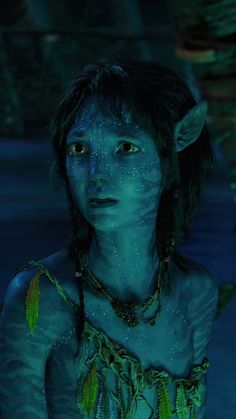 a woman with blue paint on her face and body, in the water at night