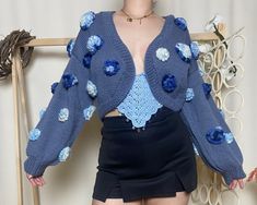 Hey there, beautiful soul! Wrap yourself in the cozy embrace of our Boho Blue Crop Cardigan, a bohemian dream come to life! Lovingly hand-knitted with a passion for craft, this chunky cardigan is as comfortable as it is stylish. The balloon sleeves add a playful touch, while the delicate crocheted daisies and hydrangea details infuse your outfit with a dash of whimsy. Whether you're lounging at home or out on a casual adventure, this cardigan is the perfect companion. And if you're looking for a Spring Blue Chunky Knit Outerwear, Casual Blue Chunky Knit Cardigan, Blue Chunky Knit Outerwear, Crocheted Daisies, Fitted Crochet Blue Cardigan, Crochet Daisies, Fitted Blue Crochet Cardigan, Chunky Flower Cardigan, Blue Hand-knitted Acrylic Sweater