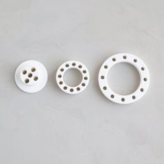 three different types of white ceramic objects on a gray surface with holes in the middle