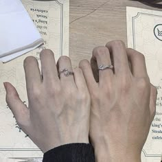 two people with wedding rings on their hands next to each other, one holding the other's hand