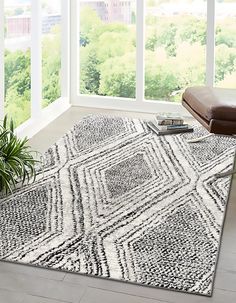 a living room with a large window and a rug on the floor in front of it