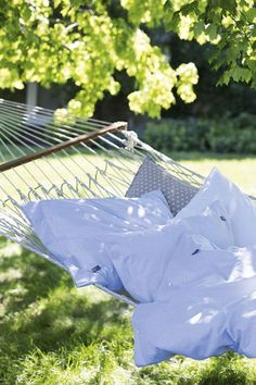 a hammock that is in the grass with some shirts hanging out on it