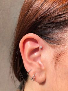 a close up of a person's ear with two piercings on it and one behind the ear