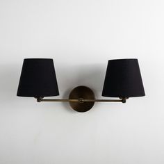 two black lamps are on the wall next to each other and one light is turned on