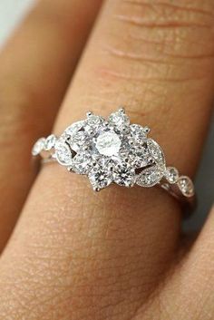 a woman's hand with a diamond engagement ring on her left hand and the center stone is surrounded by diamonds