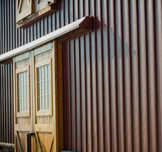 a wooden door is open on the side of a metal building that's covered in corrugated