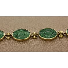 An expertly crafted estate bracelet featuring nine dark green carved nephrite bezel set in 18K yellow gold. The links are attached using ornamental gold bows. The secure discreet lock also serves as a part of the design.  Bracelet Length: 8.00 inches  Bracelet Width: 0.55 inches Luxury Carved Jewelry For Formal Occasions, Elegant Green Cabochon Bracelets, Luxury Green Engraved Jewelry, Luxury Engraved Green Jewelry, Formal Yellow Gold Intaglio Bracelets, Formal Yellow Gold Intaglio Bracelet, Yellow Gold Intaglio Bracelet For Formal Occasions, Luxury Carved Bracelet Jewelry, Elegant Carved Bracelets As Gifts