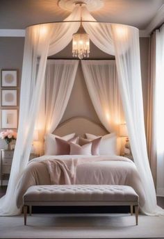 a bedroom with a canopy bed and white drapes on the ceiling, along with chandelier