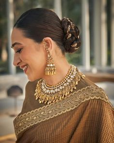 a woman in a brown sari with gold necklaces and earrings on her head