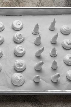 a pan filled with white icing on top of a counter next to a cookie sheet