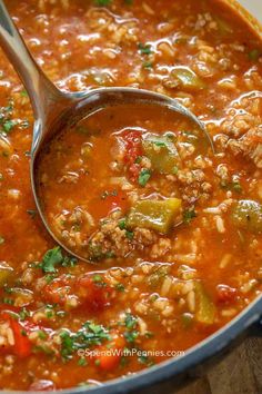 a ladle full of soup with meat and vegetables