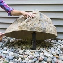 a person holding an umbrella over some rocks