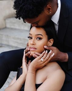 a man in a suit kissing a woman's face on the cheek while sitting down