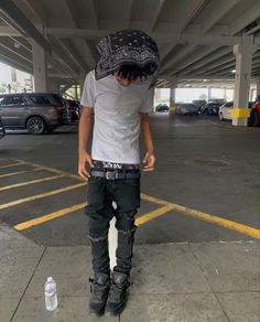 a man standing in an empty parking lot with his back to the camera, wearing black jeans and a white t - shirt