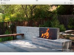 an outdoor fire pit in the middle of a park with benches and trees around it