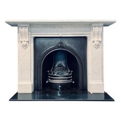 a white fireplace with a black mantle and a silver bell on it's side