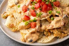 a white plate topped with nachos covered in cheese and tomatoes