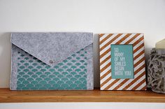 three small envelopes sitting on top of a shelf next to a vase and candle