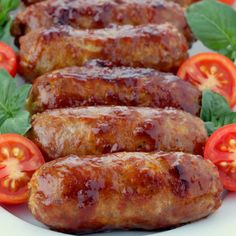 several sausages on a plate with tomatoes and basil around them, ready to be eaten