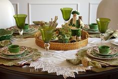 the table is set with green dishes and place settings